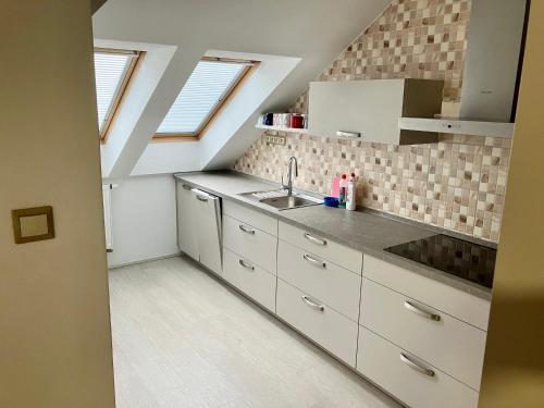 eine Küche mit weißen Schränken und einem Waschbecken in der Unterkunft Sebastian Apartments in Třeboň