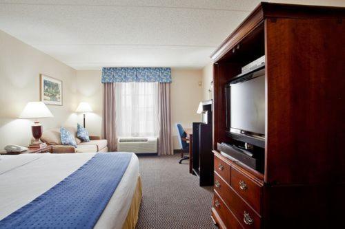 a hotel room with a bed and a flat screen tv at Holiday Inn Express & Suites Newport News by IHG in Newport News