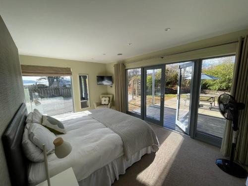 ein Schlafzimmer mit einem großen Bett und Glasschiebetüren in der Unterkunft Carnanamish in Tobermory