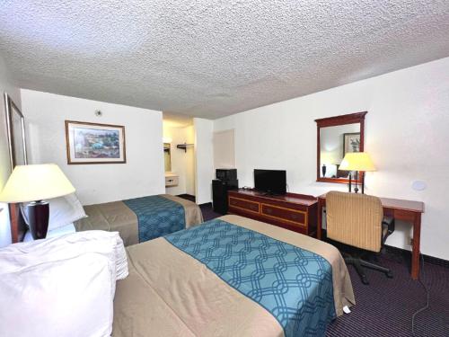 a hotel room with two beds and a desk at Heritage Inn and Suites in Baton Rouge