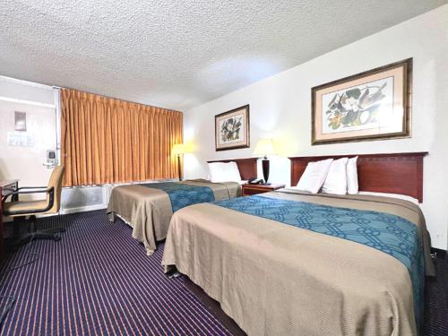 a hotel room with two beds and a desk at Heritage Inn and Suites in Baton Rouge