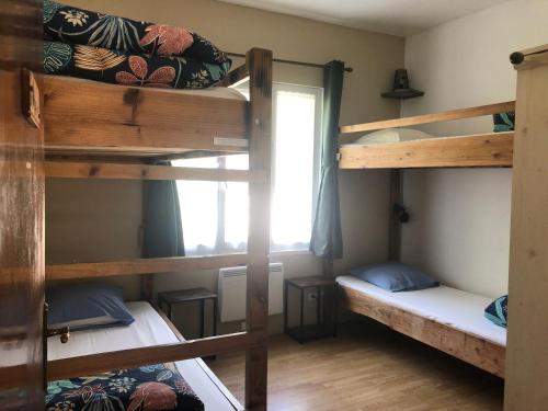 une chambre avec trois lits superposés et une fenêtre dans l'établissement Gîte Le Nébuzon, à Rosis