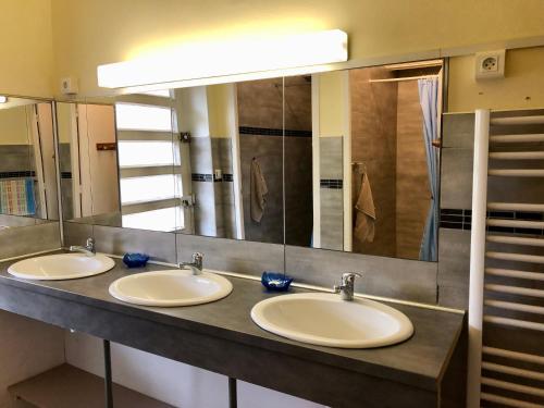 La salle de bains est pourvue de 3 lavabos et d'un grand miroir. dans l'établissement Gîte Le Nébuzon, à Rosis
