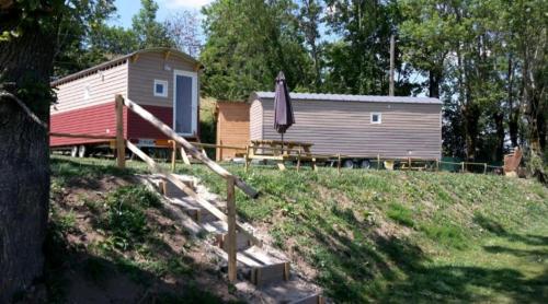 una cabaña con una mesa y una sombrilla delante de ella en Logement insolite au cœur de l'Auvergne, en Rochefort-Montagne