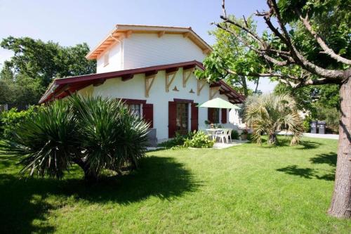 a small white house with a grass yard at Villa Robert Shumann, à 700 m de la plage in Andernos-les-Bains