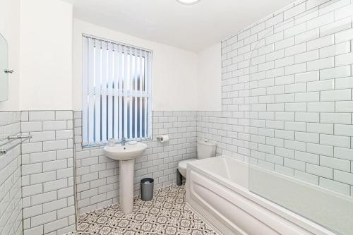 un bagno bianco con lavandino e vasca di 3 Bedroom Holiday Home within Kensington a Liverpool