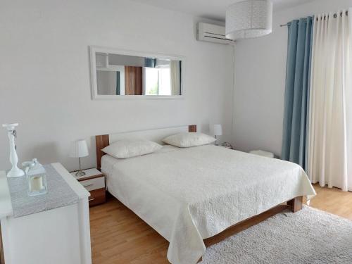 een witte slaapkamer met een bed en een spiegel bij Apartments Marija Anchor in Zadar