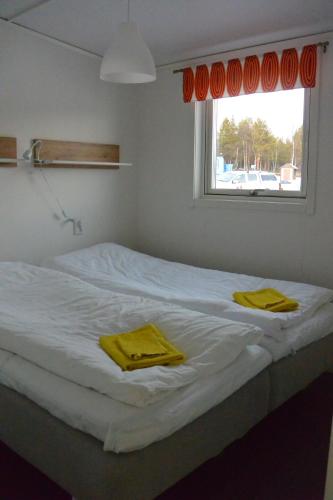 a white bed with two yellow towels on it at Ofelaš Islandshästar & Guideservice in Kiruna