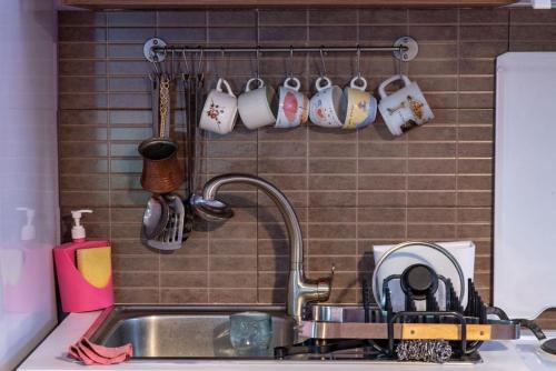 a kitchen sink with mugs hanging on a wall at Minodora's Guesthouse in Dikorfo