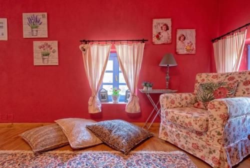 a living room with red walls and a chair and a window at Minodora's Guesthouse in Dikorfo