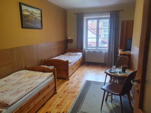 a room with two beds and a table and a window at Penzión U Jakuba in Kežmarok