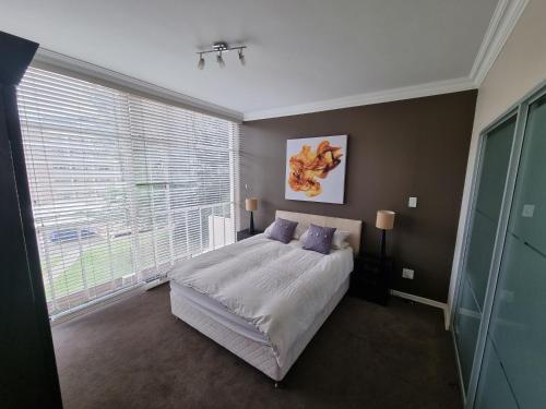 a bedroom with a bed and a large window at Walk frm Mandela Square, Sandton City and Gautrain in Johannesburg