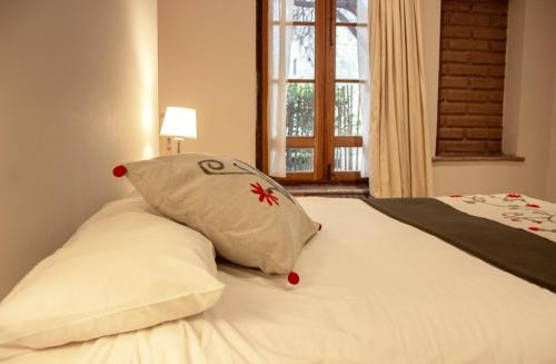 a bed with two pillows on it with a window at Vieja Posada Hotel Histórico in Cafayate