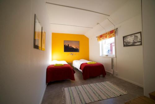 a room with two beds with red sheets and a window at Ofelaš Islandshästar & Guideservice in Kiruna