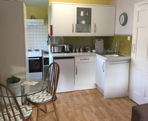 cocina con armarios blancos, mesa y sillas en Courtyard Flat - Kendal, en Kendal