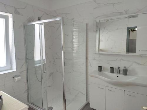 een witte badkamer met een douche en een wastafel bij Apartments Marija Anchor in Zadar