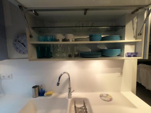 a kitchen counter with a sink and a shelf with dishes at Park view apartment near Panormou in Athens