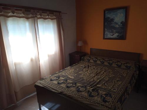 1 dormitorio con 1 cama y una ventana con cortinas en Amplia casa con estacionamiento cerca del mar en Mar de Ajó