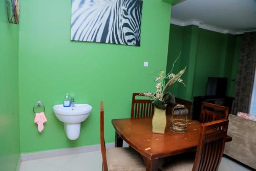 a bathroom with green walls and a table and a sink at Karibu Namugongo in Kampala