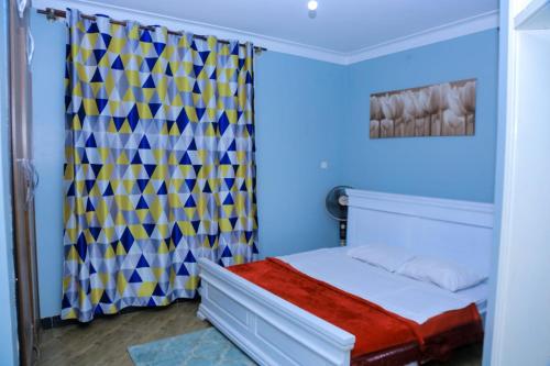 1 dormitorio con cama y cortina en Karibu Namugongo, en Kampala