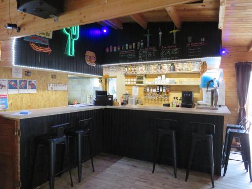 un bar dans un restaurant avec tabourets au comptoir dans l'établissement Lodge Les P'tites Maisons dans la Prairie, à Sallertaine