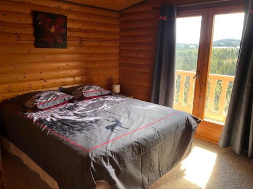 Bett in einem Blockhaus mit Fenster in der Unterkunft CHALET CAPRICES DES CIMES in Bolquere