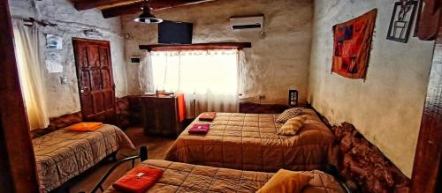 a bedroom with two beds and a window at La Amanecida Tilcara Departamento tipo estudio in Tilcara