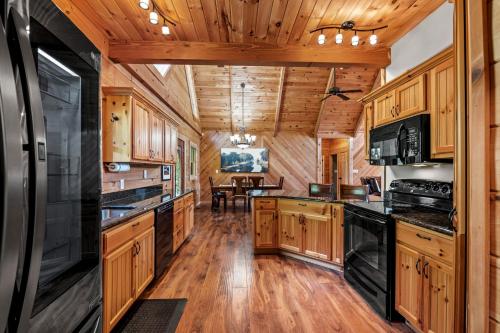 a kitchen with wooden cabinets and black appliances at Peace in the Valley - Mtn VIEWS w/HotTub, GameRoom, Theatre, Arcade in Sevierville