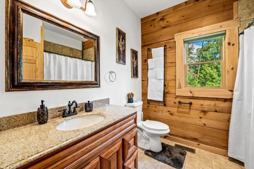 a bathroom with a sink and a toilet and a mirror at Peace in the Valley - Mtn VIEWS w/HotTub, GameRoom, Theatre, Arcade in Sevierville
