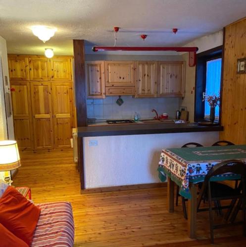 una cocina con armarios de madera y una mesa en una habitación en Le chalet du skieur en La Thuile