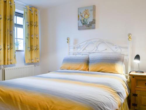 1 dormitorio con 1 cama con cortinas amarillas en Meadow Lodge-e4105 en Aspatria