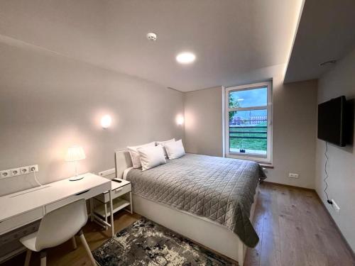 um quarto com uma cama, uma secretária e uma janela em Victoria Old Town Apartments em Klaipėda