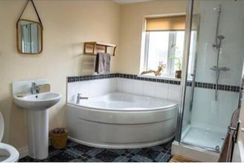 a bathroom with a tub and a sink and a shower at Spacious Family Home Minutes from the Beach in Blackpool