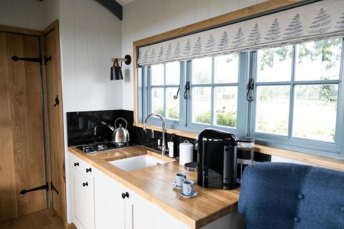 een keuken met een wastafel en 2 ramen bij Skylark Shepherds Hut in Bath