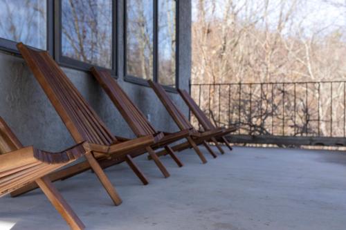 three wooden chairs sitting on a balcony with windows at The Edelweiss Estate - Mountain Views in Gatlinburg