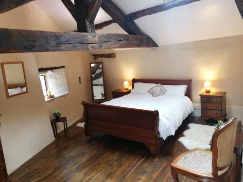 an attic bedroom with a bed and two chairs at Les Granges de la Leigne, Ruffec in Condac
