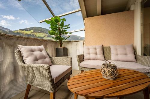 a patio with wicker chairs and a wooden table at Gästehaus Wiesengrund & Apart Sporer in Mayrhofen