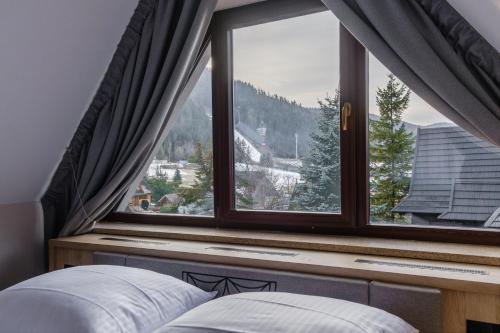 a bedroom with a window with a mountain view at Wielka Krokiew Residence&SPA - Zakopane - JACUZZI, SAUNA, TĘŻNIA SOLANKOWA, SPA, GRILL in Zakopane