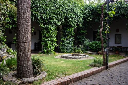 a garden with two trees and a fountain at Vieja Posada Hotel Histórico in Cafayate