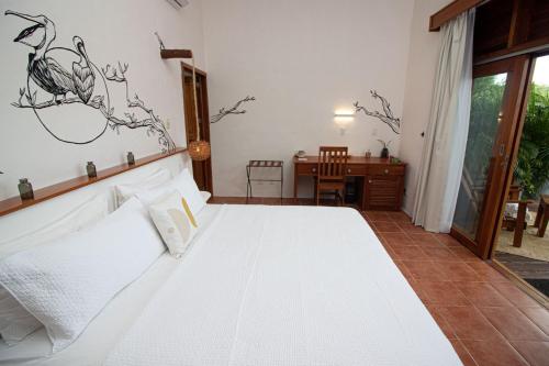 a bedroom with a white bed and a desk at Hotel Casa HX - Adults Only in Holbox Island