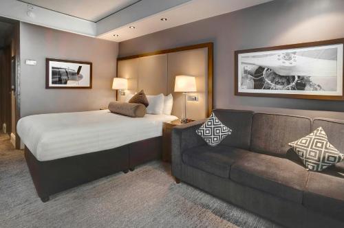 um quarto de hotel com uma cama e um sofá em Sandman Signature London Gatwick Hotel em Crawley