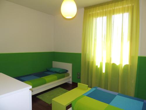 a green and white room with two beds and a window at Ross House in Fermo