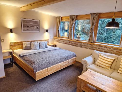 a bedroom with a bed and a couch and windows at Pension Linda in Harrachov