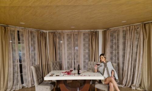 a woman sitting at a table with a glass of wine at Homoljski pogled Banja Zdrelo in Ždrelo