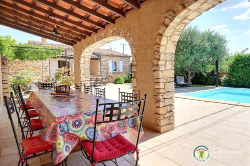 un patio avec une table et des chaises et une piscine dans l'établissement Villa L'Opaline 10 pers Piscine privée Chauffée Animaux admis Wifi, à Salavas
