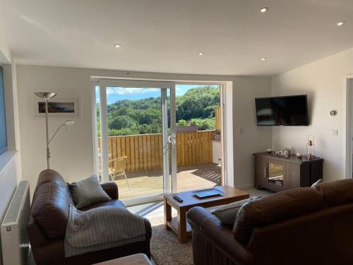 a living room with a couch and a table and a television at Sunny Nook, Pretty 1 bed modern cottage close to Woolacombe in Ilfracombe