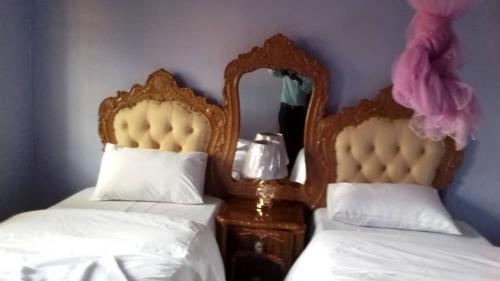 a bedroom with two beds with white sheets and a mirror at Faigib Guest House in Chipata