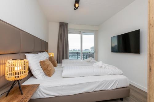 een slaapkamer met een groot bed en een televisie bij Appartement Vista Maris, Havenweg 8-1, St. Annaland in Sint Annaland