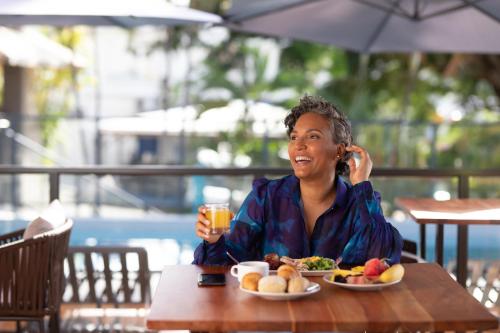 a woman sitting at a table with a plate of food at Karibea Squash Hôtel in Fort-de-France