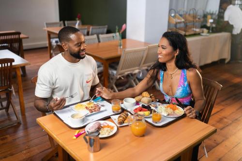 a man and a woman sitting at a table eating food at Karibea Squash Hôtel in Fort-de-France
